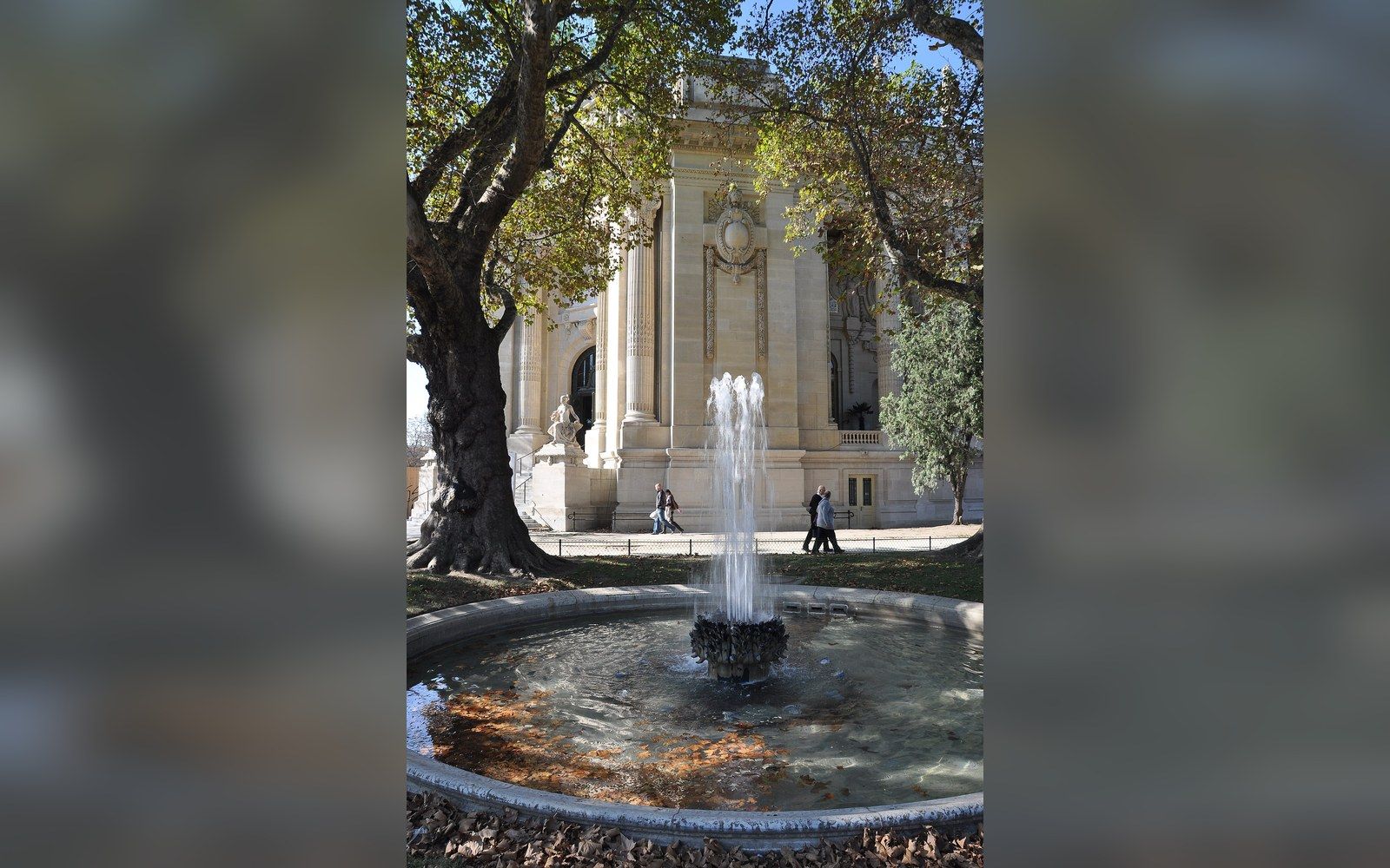 Fountain spraying in a garden pool near the Grand Palais's columned facade